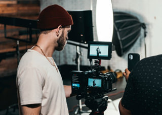 Man looking at the display of a video camera as he films